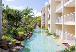 Un hôtel doté d’un élément aquatique, de palmiers et de balcons.