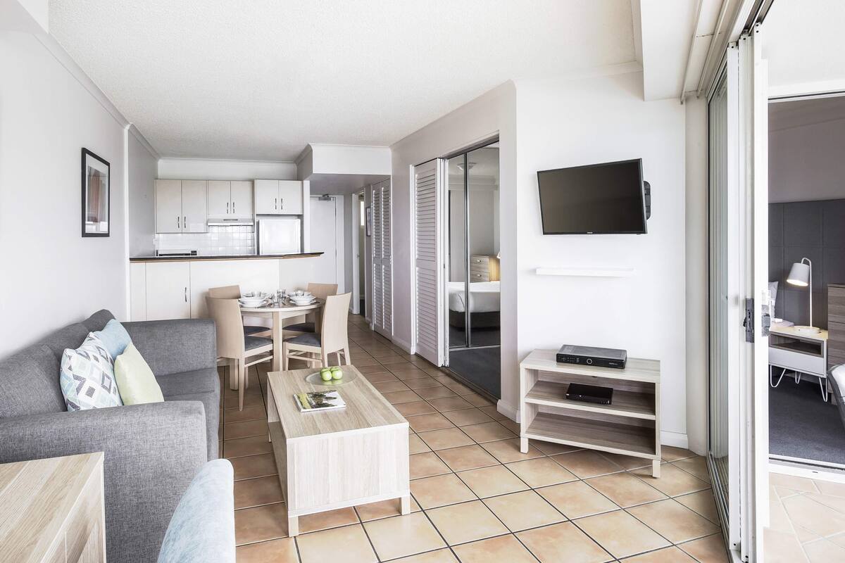 A modern apartment with a living room, dining area, kitchenette, and a bedroom with a sliding door.