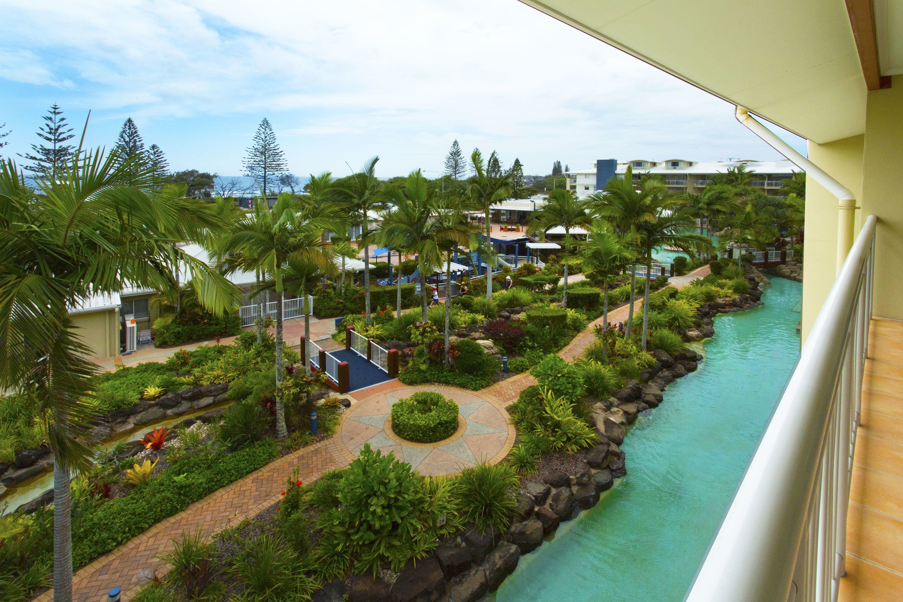 A resort with a water feature, palm trees, and a pool area.