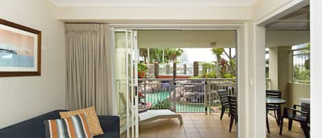 A living room with a sofa, a coffee table, and a view of an outdoor pool area.