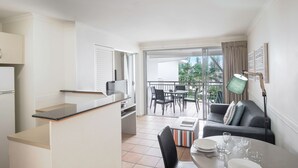 A modern kitchen with a dining area, a balcony with a table and chairs, and a sofa.