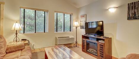 A living room with a sofa, a coffee table, a TV, and a fireplace.