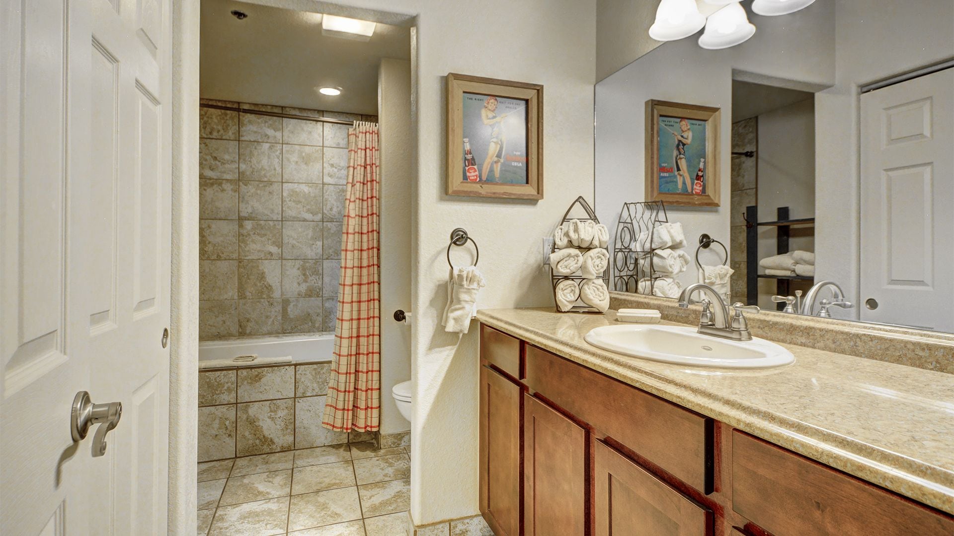 A bathroom with a bathtub, shower curtain, sink, and towel racks.