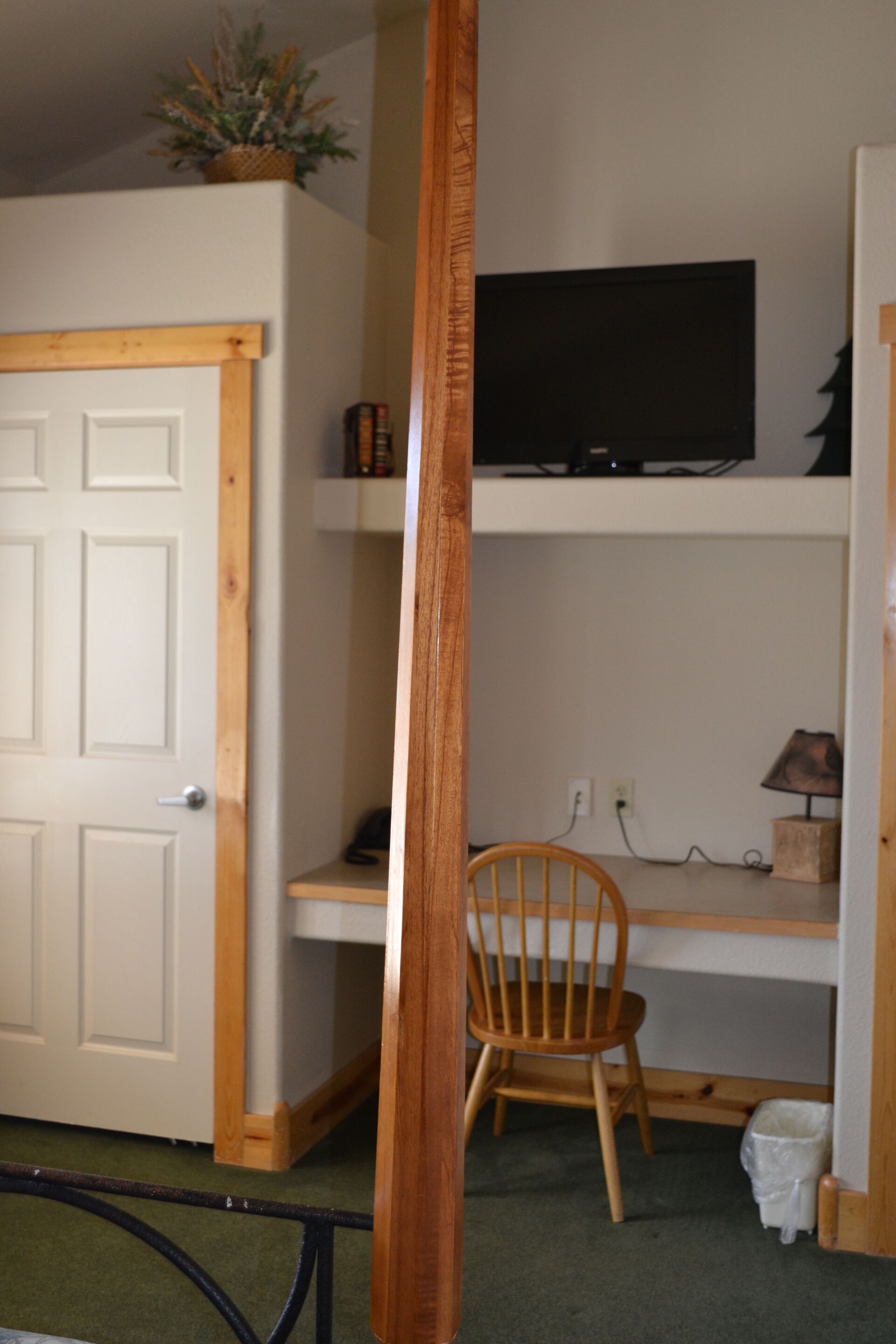 A room with a wooden door, a television on a shelf, a chair, and a small table.