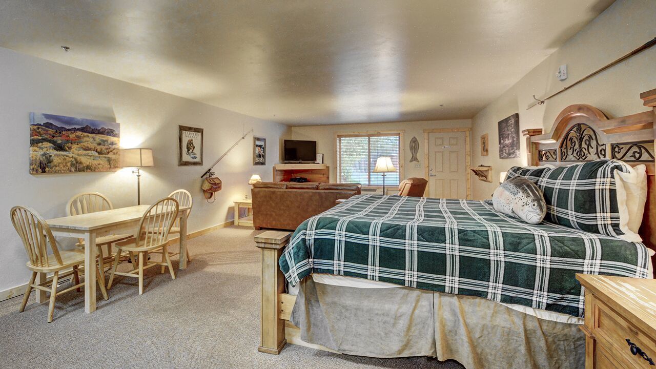 Une chambre à coucher avec un lit, un bureau, des chaises, une télévision et une fenêtre.