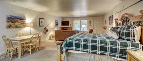 A bedroom with a bed, a desk, chairs, a TV, and a window.