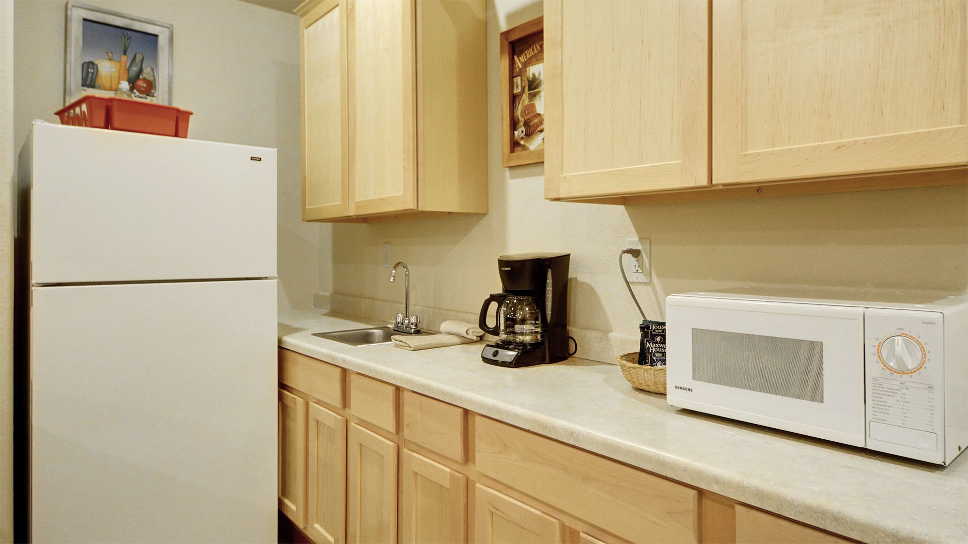 A kitchen with wooden cabinets, a white refrigerator, a coffee maker, and a microwave.