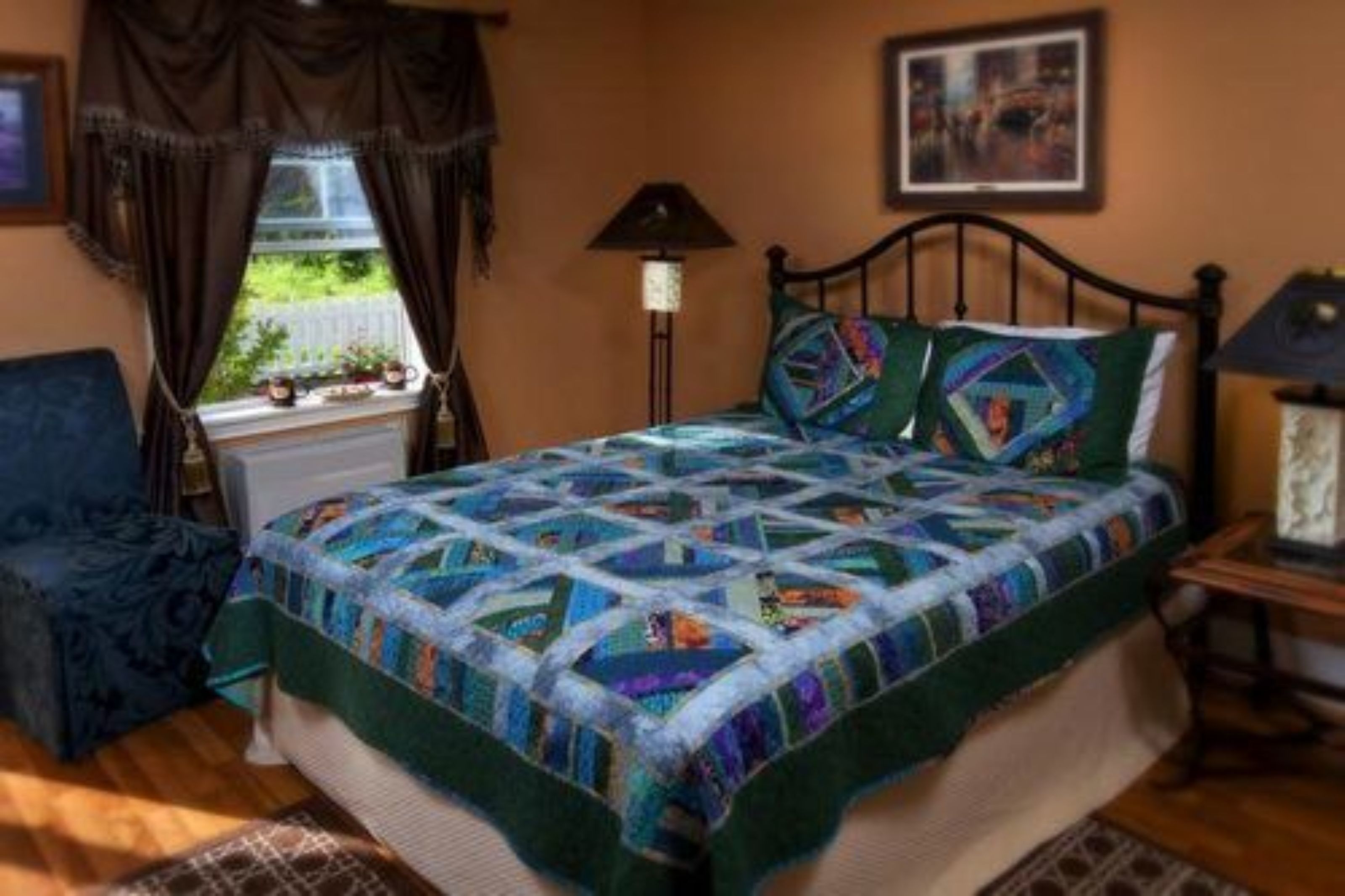 A bedroom with a bed, a chair, a lamp, and a window with curtains.