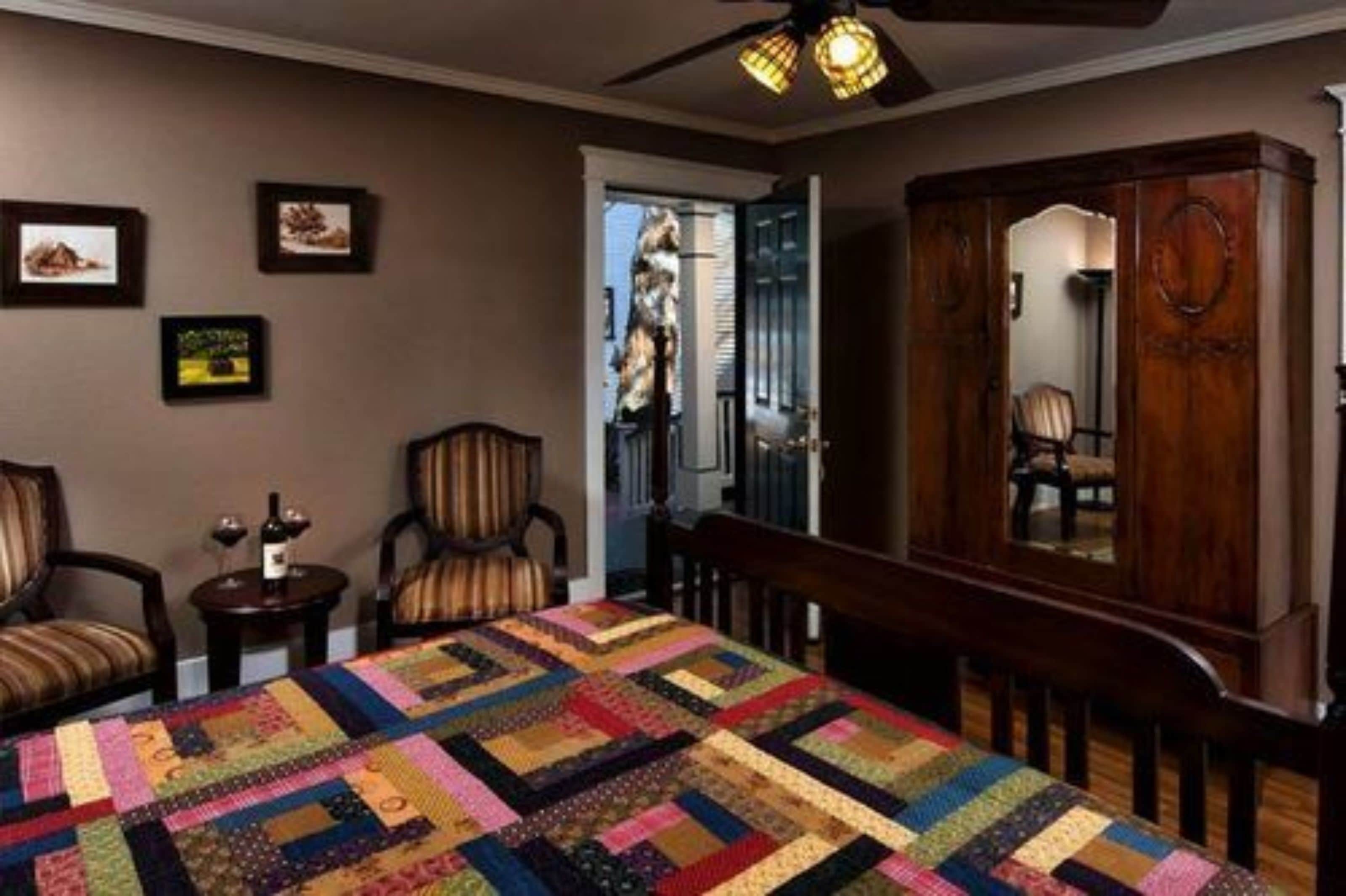 Una habitación con un edredón acolchado grande, muebles de madera y cuadros en la pared.