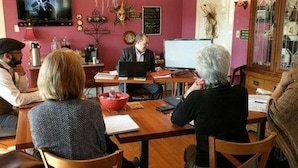 A group of people in a room with a wooden table, a laptop, and various items on the table. - The Carriage House B&B (Jefferson)