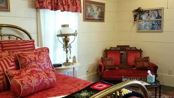 Ein traditionell eingerichtetes Schlafzimmer mit einem Bett, einer Couch, einer Lampe und gerahmten Kunstwerken an den Wänden.