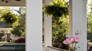 A dining table set outdoors with various dishes and drinks, surrounded by wicker chairs. - The Carriage House B&B (Jefferson)
