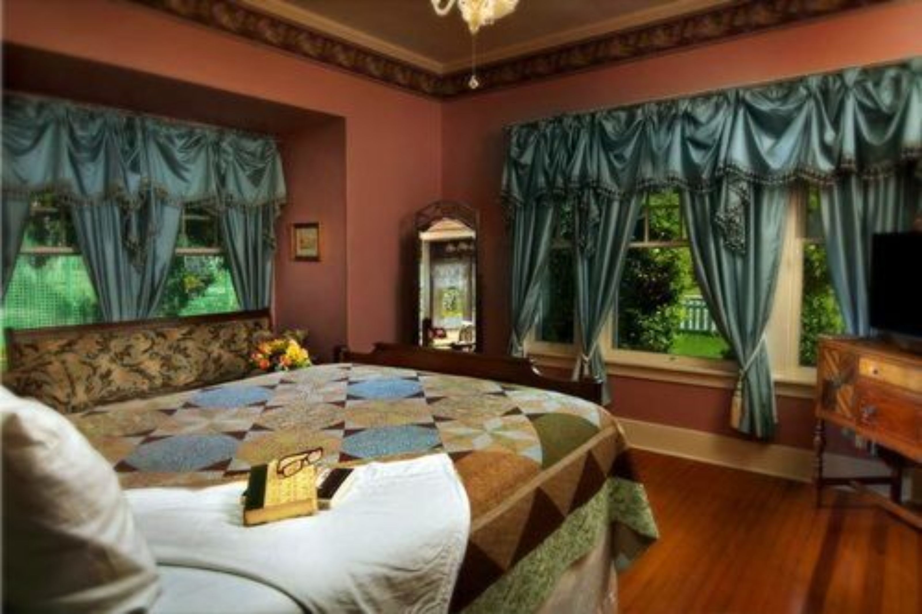 Een slaapkamer met een groot bed, een dressoir en een raam met gordijnen.