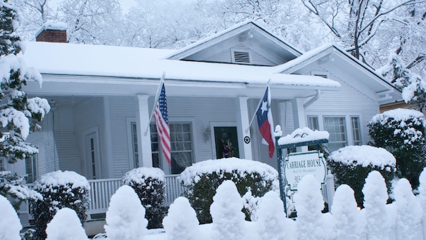 A white house with a porch, two flags, and a sign indicating it is a carriage house. - The Carriage House B&B (Jefferson)