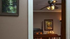A bathroom with a bathtub filled with rose petals, a ceiling fan, and a framed picture on the wall. - The Carriage House B&B (Jefferson)