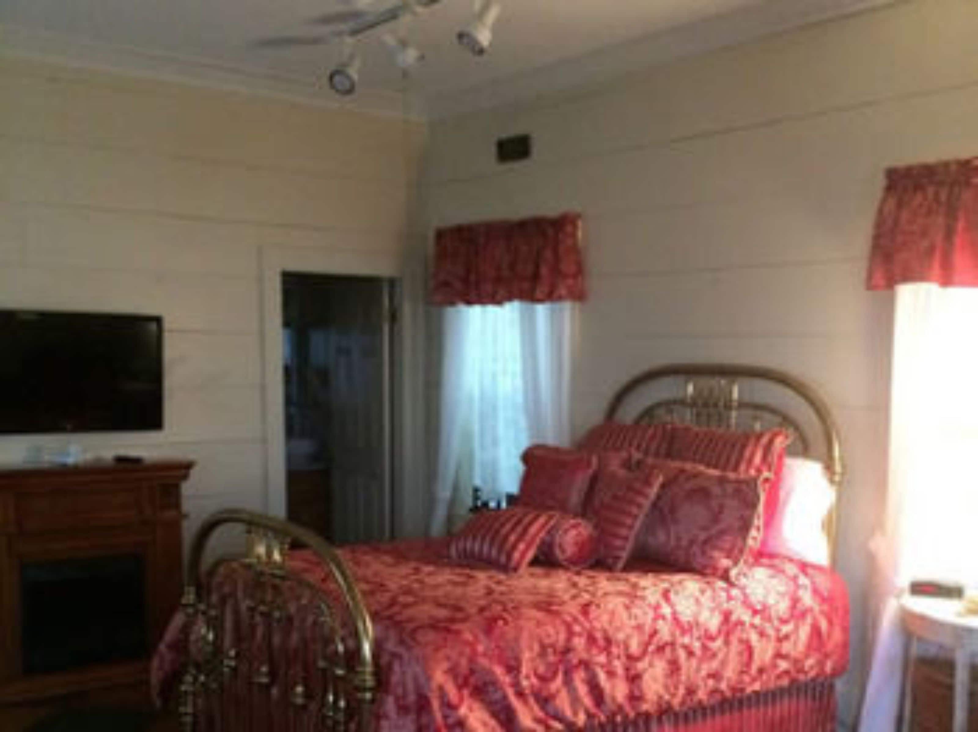 A bedroom with a bed, a television, and a dresser.