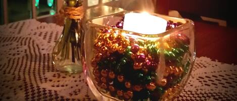 A table with a glass candle holder containing colorful beads and a vase with flowers.
