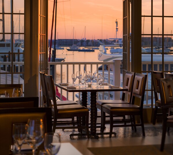 A dining area with a table set for four, overlooking a marina with boats. - Forty 1 North (Newport)
