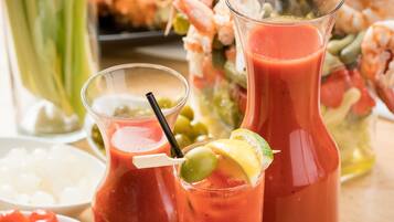 Una mesa con dos vasos de Bloody Mary, una jarra de Bloody Mary y un bol de camarones.