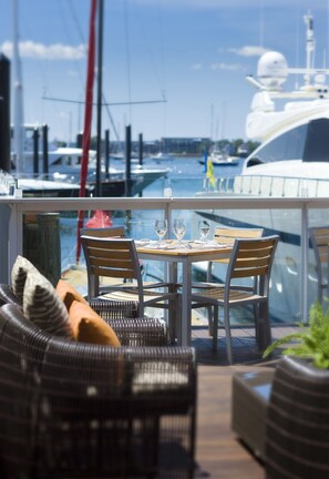 A dining area with a table set for two, overlooking a marina with boats. - Forty 1 North (Newport)