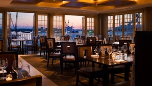 A restaurant with tables set for dining, large windows offering a view of the cityscape, and a modern ceiling design. - Forty 1 North (Newport)