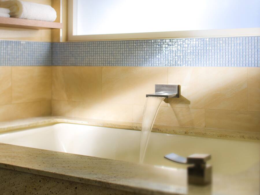 Ein Badezimmer mit einer Badewanne, einem Handtuchhalter und einer Kachelwand.
