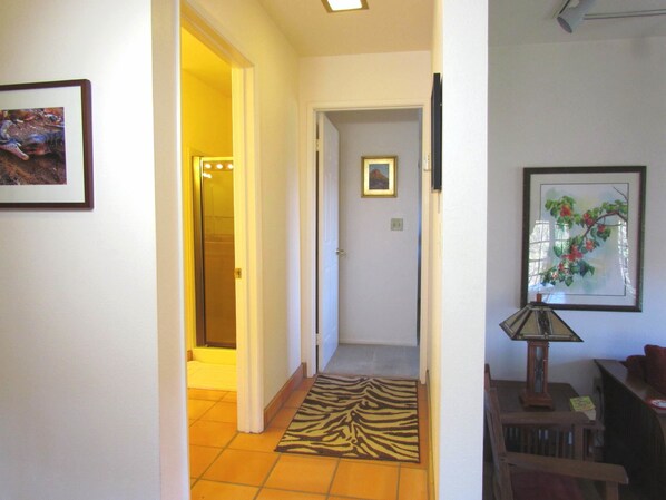 A hallway with a zebra-patterned rug, a framed picture on the wall, and a lamp on a table.