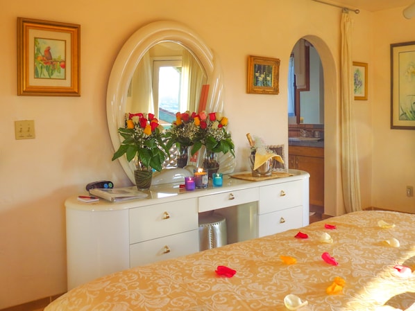 A bedroom with a bed, a dresser with a mirror, and a vase with flowers. - Topanga Canyon Inn B&B (Topanga)