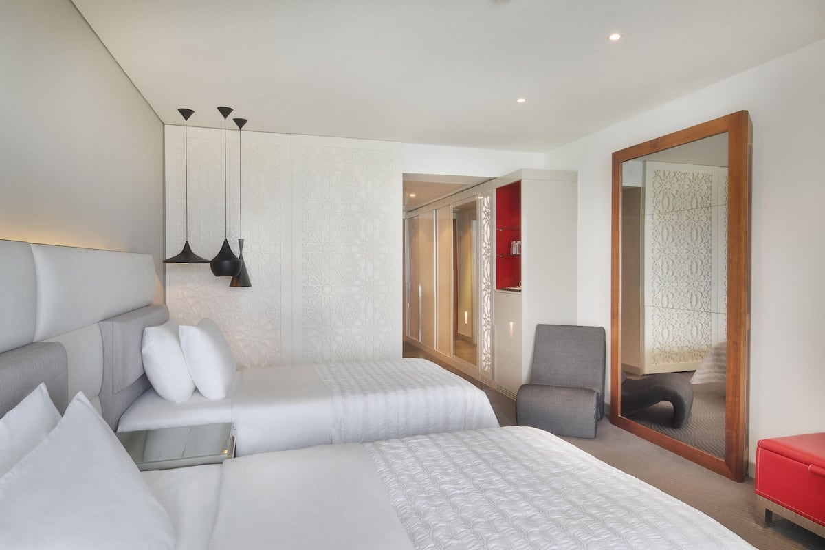 Une chambre d’hôtel moderne dotée d’un grand lit, d’un coin salon, d’un miroir et d’une armoire.