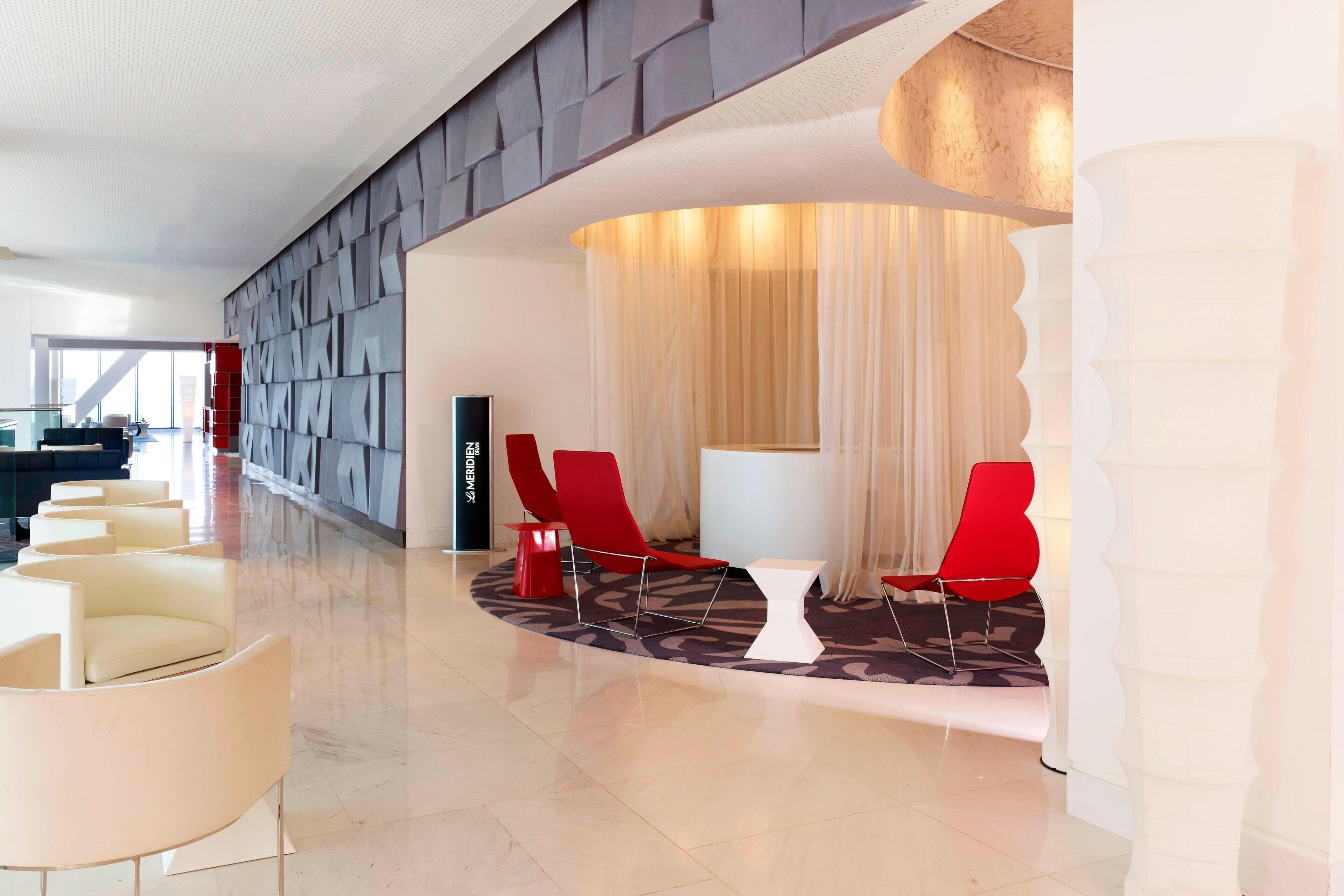 A modern lobby with a curved seating area, a reception desk, and a patterned carpet.