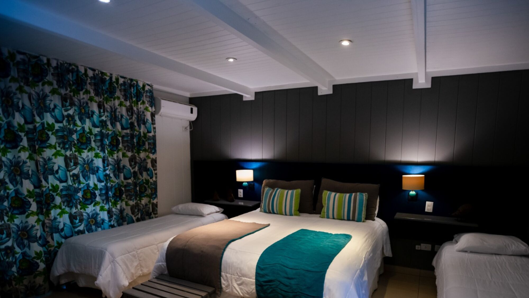A hotel room with two beds, a dark wooden headboard, and two bedside lamps.