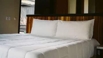 A bed with white bedding in a room with wooden headboard and beige walls.