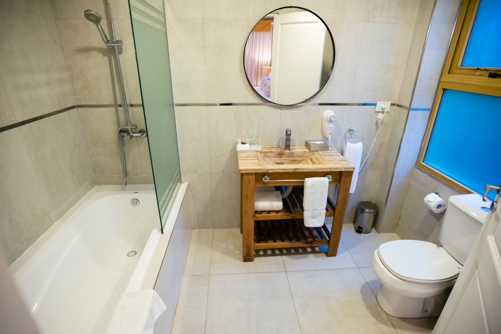 Ein Badezimmer mit einer Badewanne, einem Holzkosmetikschrank mit Spiegel, einer Toilette und einer Duschkabine aus Glas.