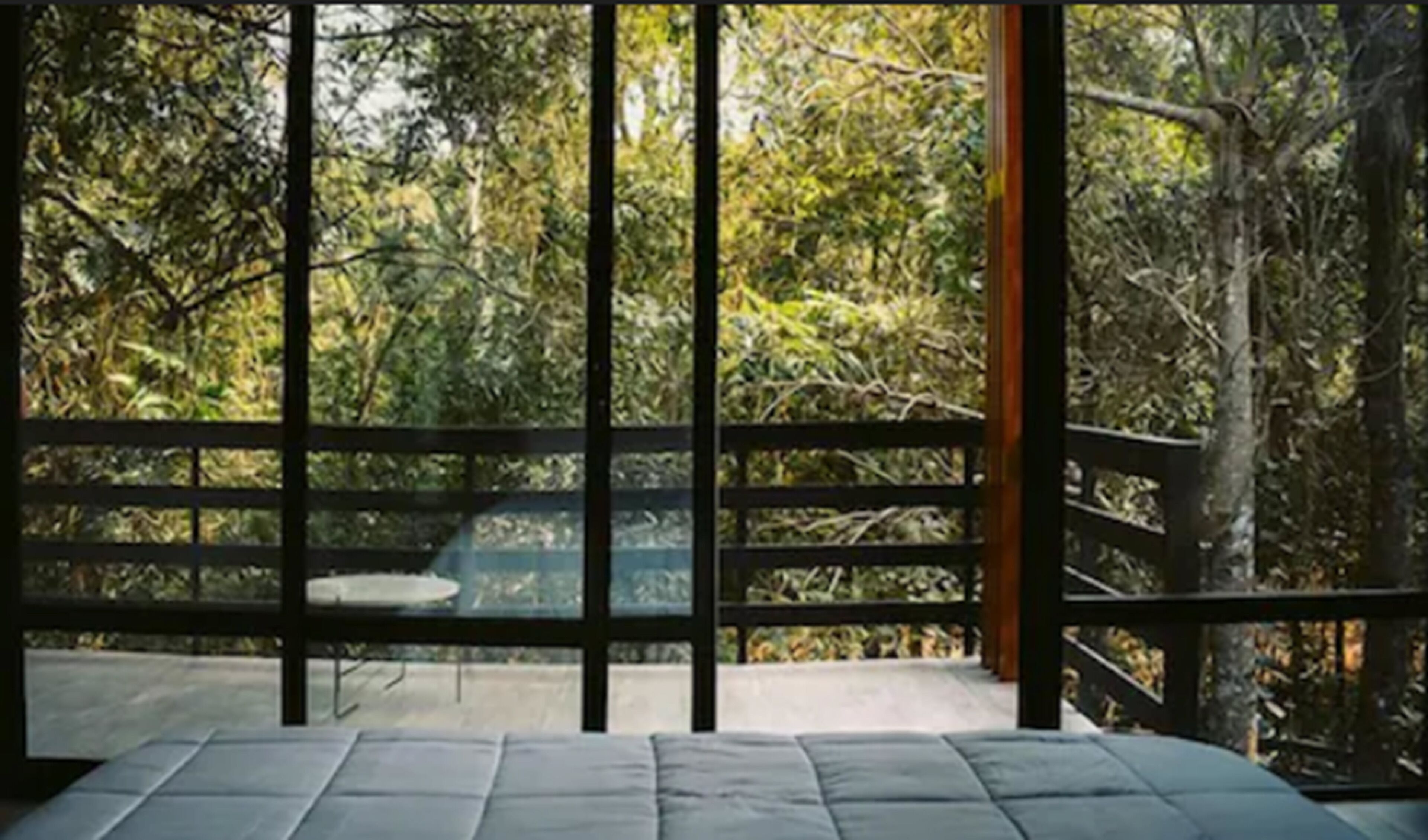 A room with a large window overlooking a forested area.