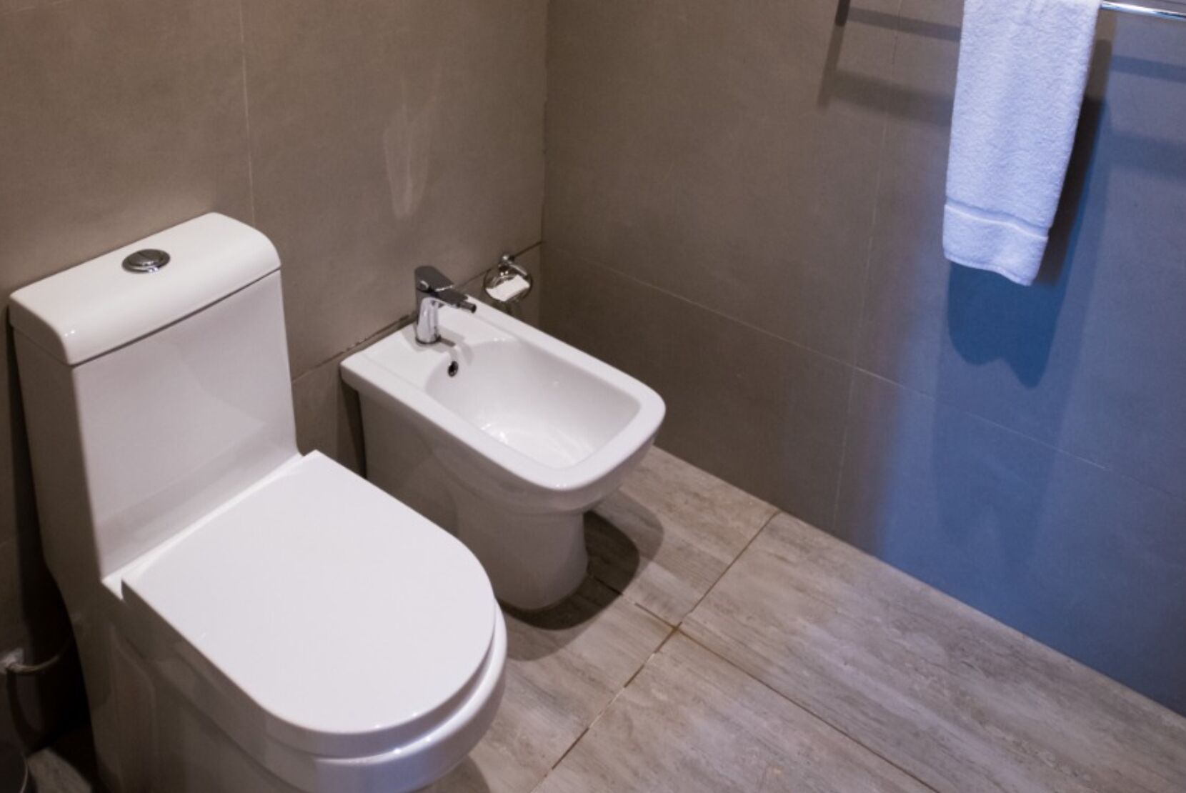 Um banheiro moderno com vaso sanitário e bidê, paredes revestidas de azulejos e área de chuveiro.