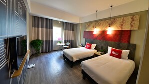 A hotel room with two beds, a TV, a desk, and a window with curtains. - ibis Xiamen Kaiyuan (Xiamen)