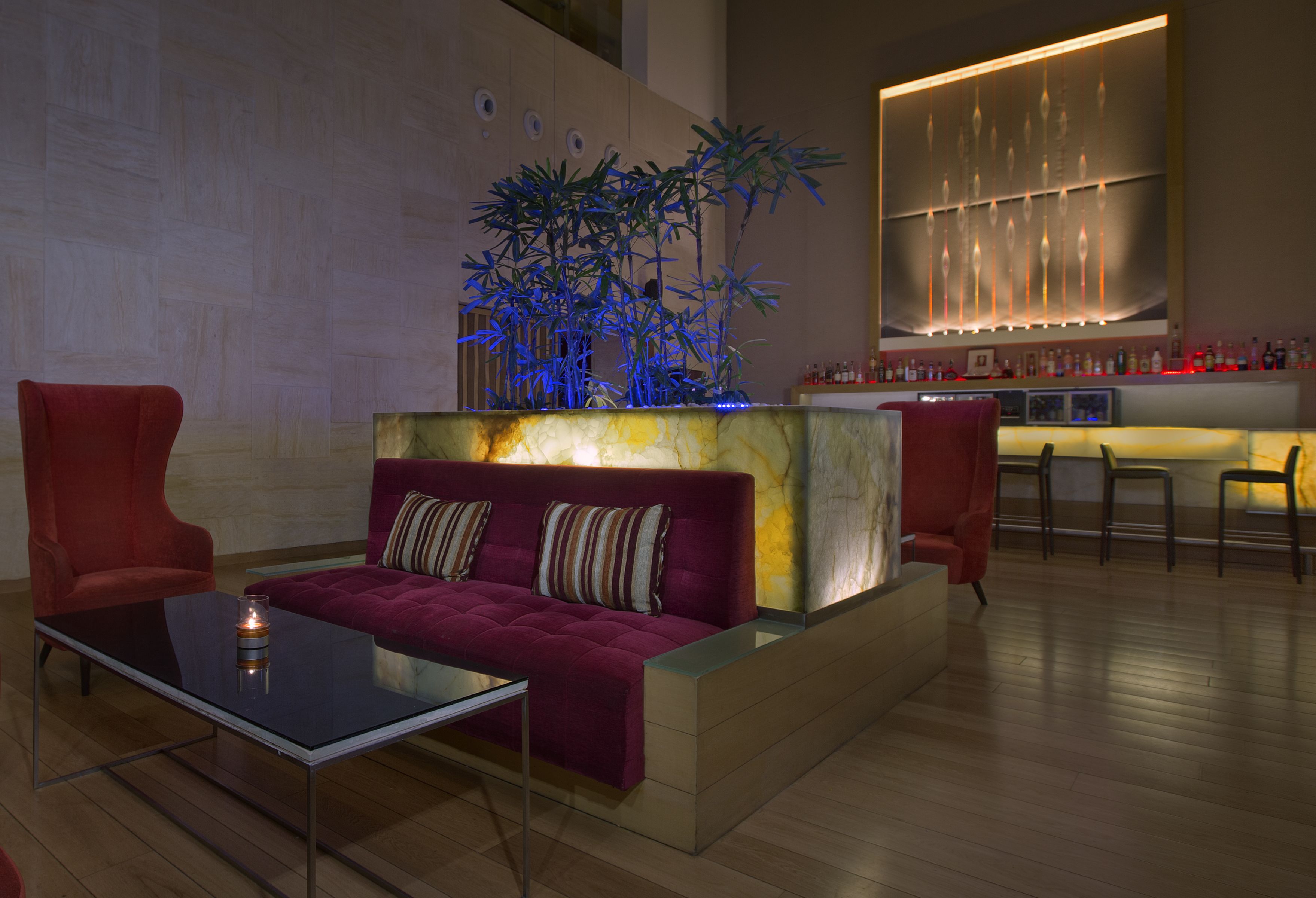 A modern living area with a sofa, armchairs, a glass coffee table, and a decorative plant.