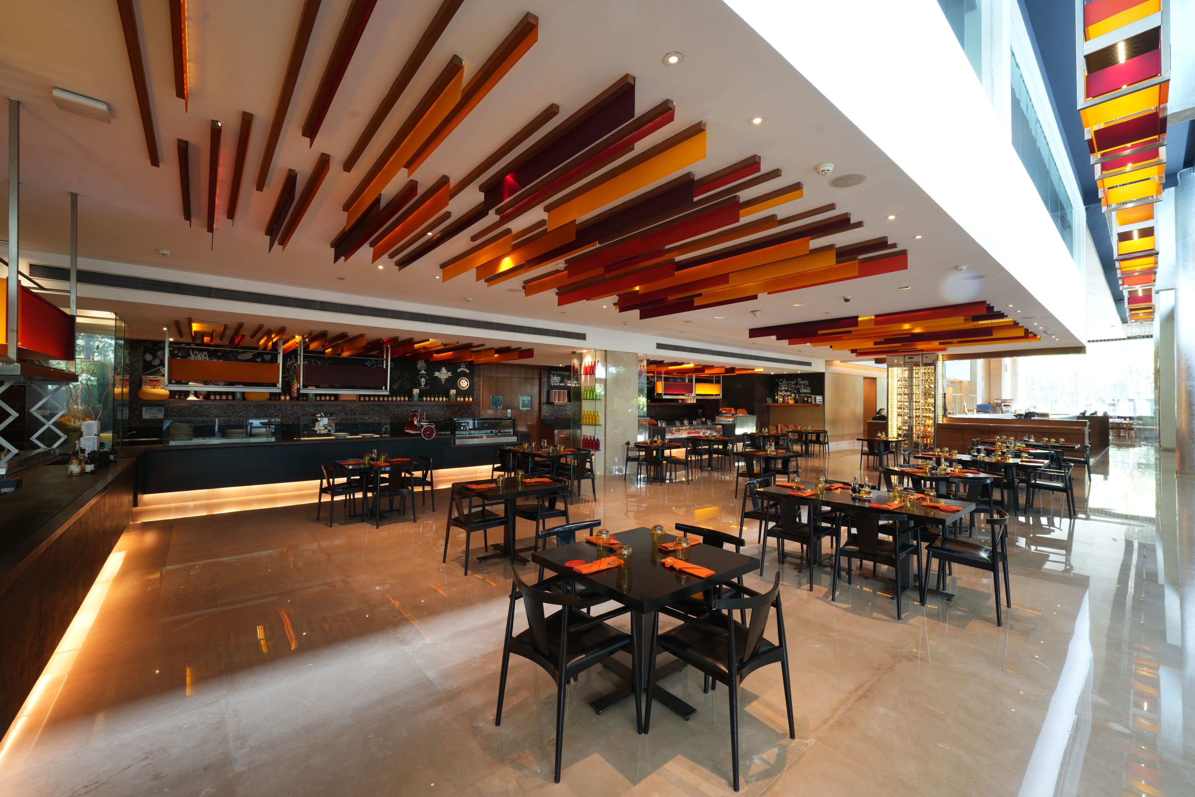 Un restaurante espacioso con decoración moderna, que cuenta con una barra larga y varias mesas.