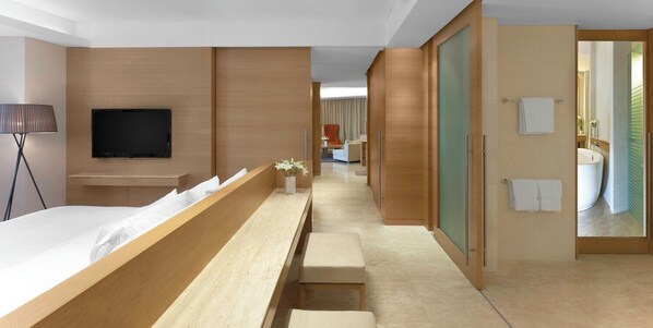 Una habitación de hotel moderna con cama, televisor, escritorio y baño a la vista a través de una puerta abierta.