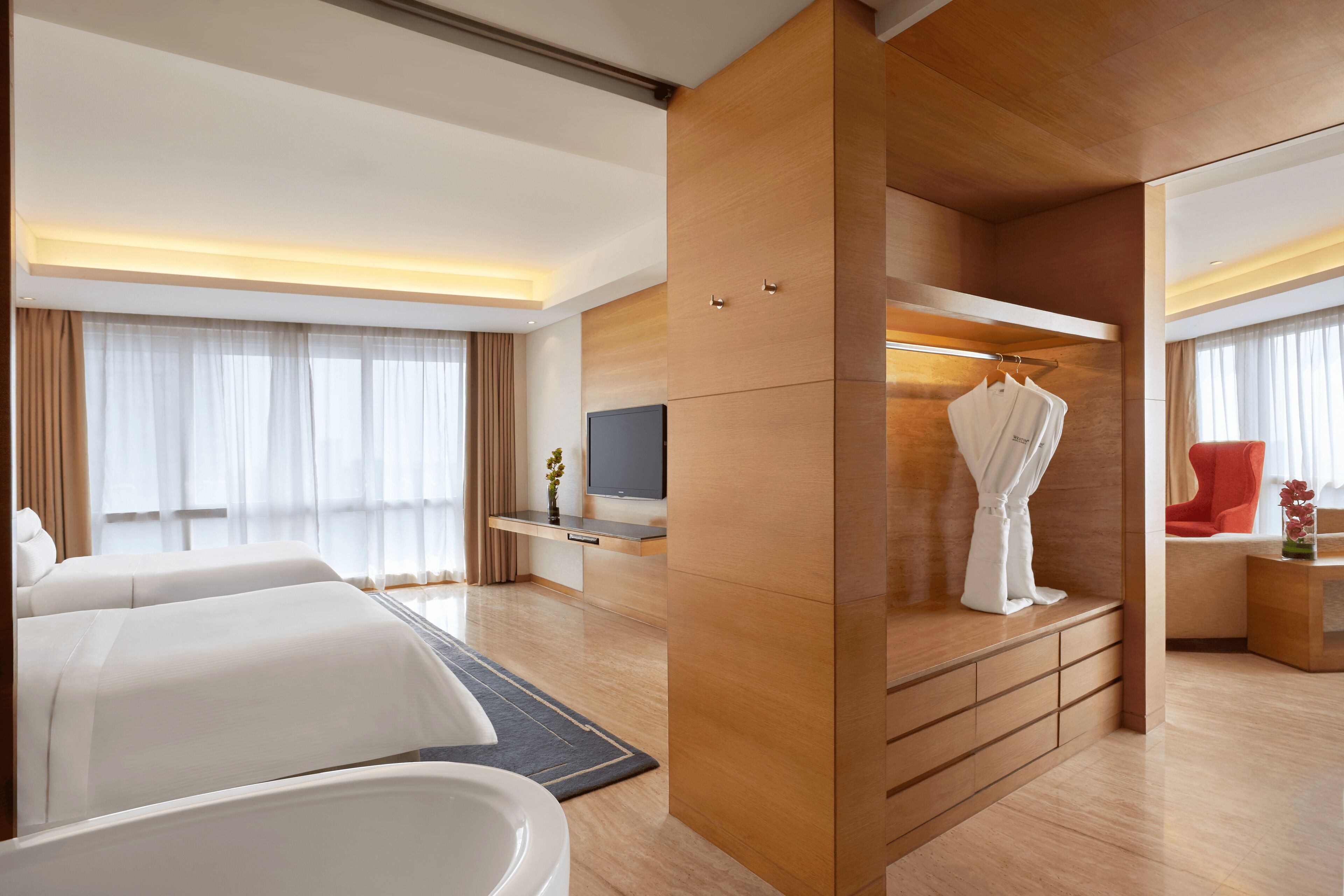 Habitación de hotel con una cama grande, televisión, armario de madera y escritorio con silla.