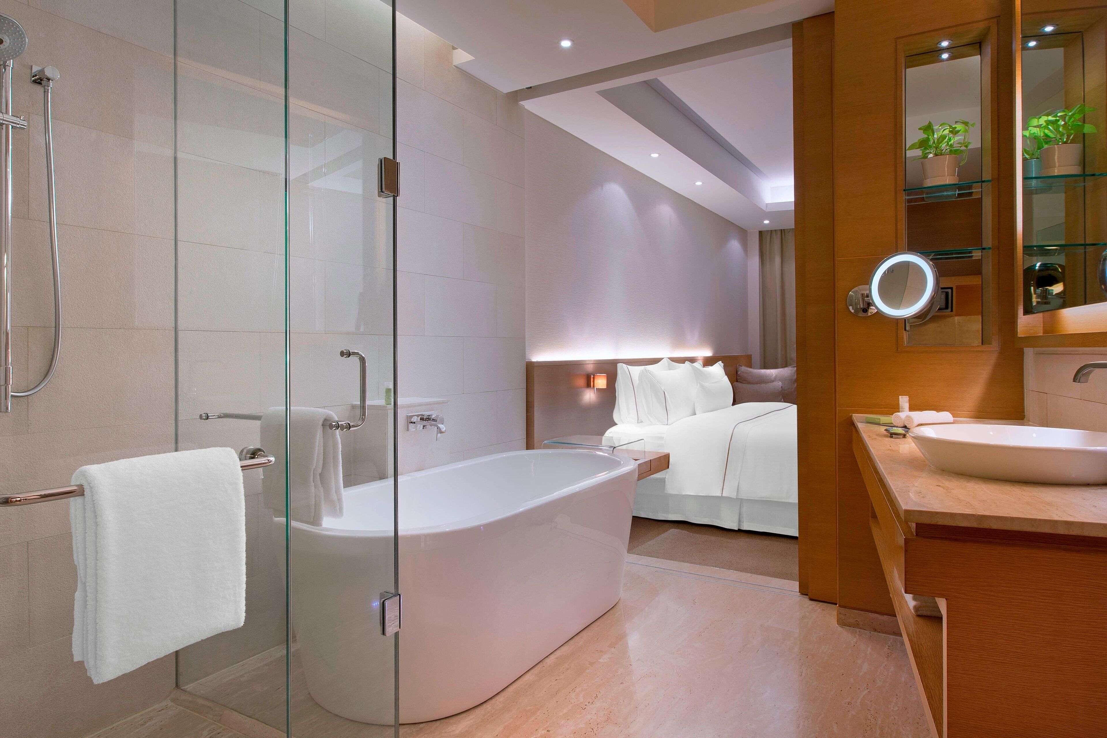 A modern bathroom with a glass-enclosed shower, a freestanding bathtub, a vanity with a sink, and a mirror.
