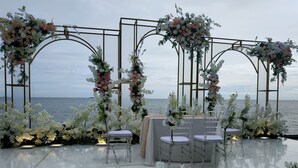 Decoración para boda al aire libre con vista despejada al mar, con adornos florales y arreglos de asientos.