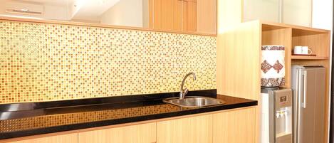 Una cocina moderna con salpicadero de azulejos, un lavamanos de acero inoxidable, armarios de madera y un refrigerador empotrado.