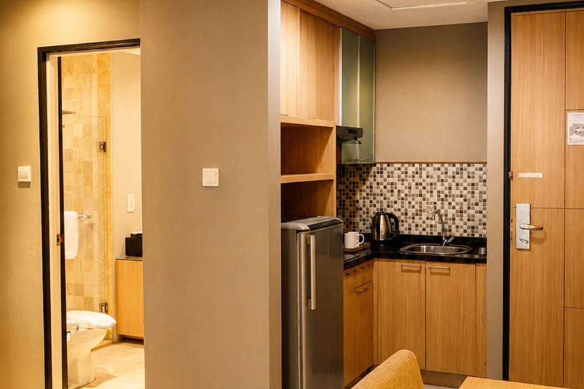 A compact kitchen with a refrigerator, coffee maker, and sink.