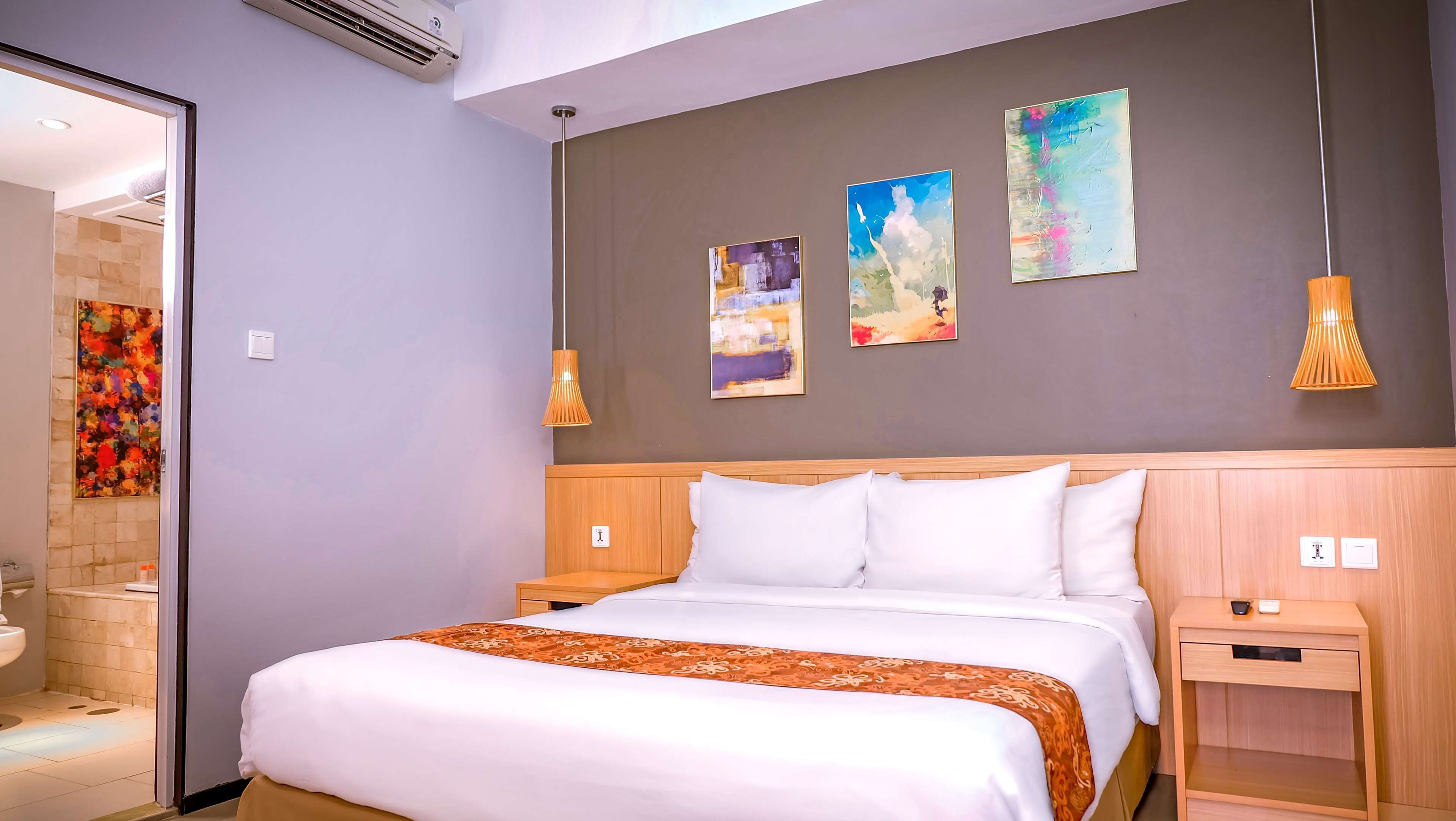 Una habitación de hotel con cama, mesitas de noche y obras de arte en las paredes.