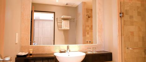 A bathroom with a large mirror, a white sink, and a glass shower enclosure.