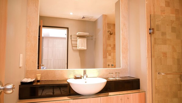 Une salle de bain avec un grand miroir, un lavabo blanc et une douche à parois de verre.