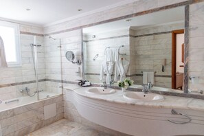 A bathroom with two sinks, a bathtub, and a large mirror. - Tunis Grand Hotel (Ariana)