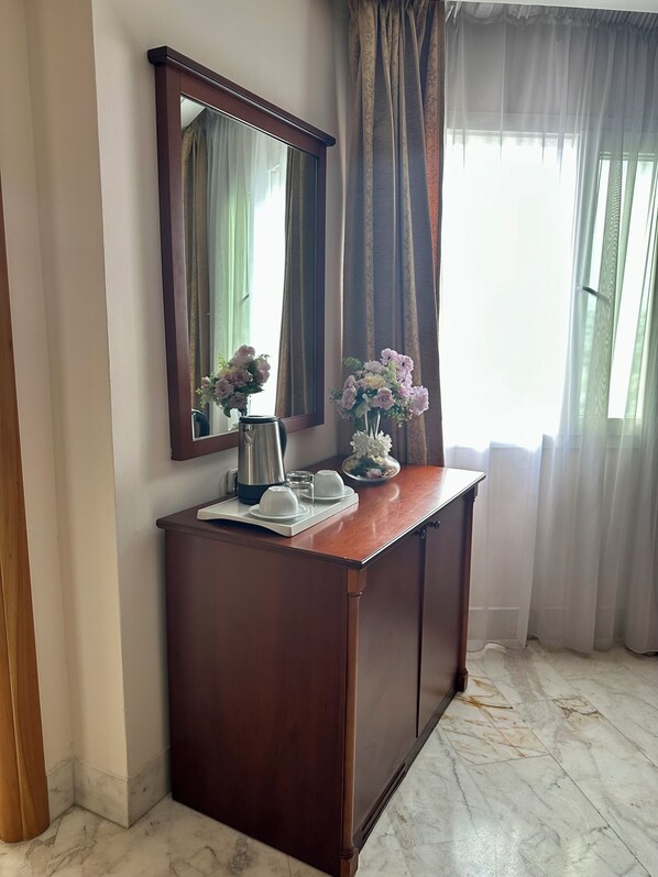 A wooden desk with a mirror, a coffee pot, cups, and a vase of flowers. - Tunis Grand Hotel (Ariana)