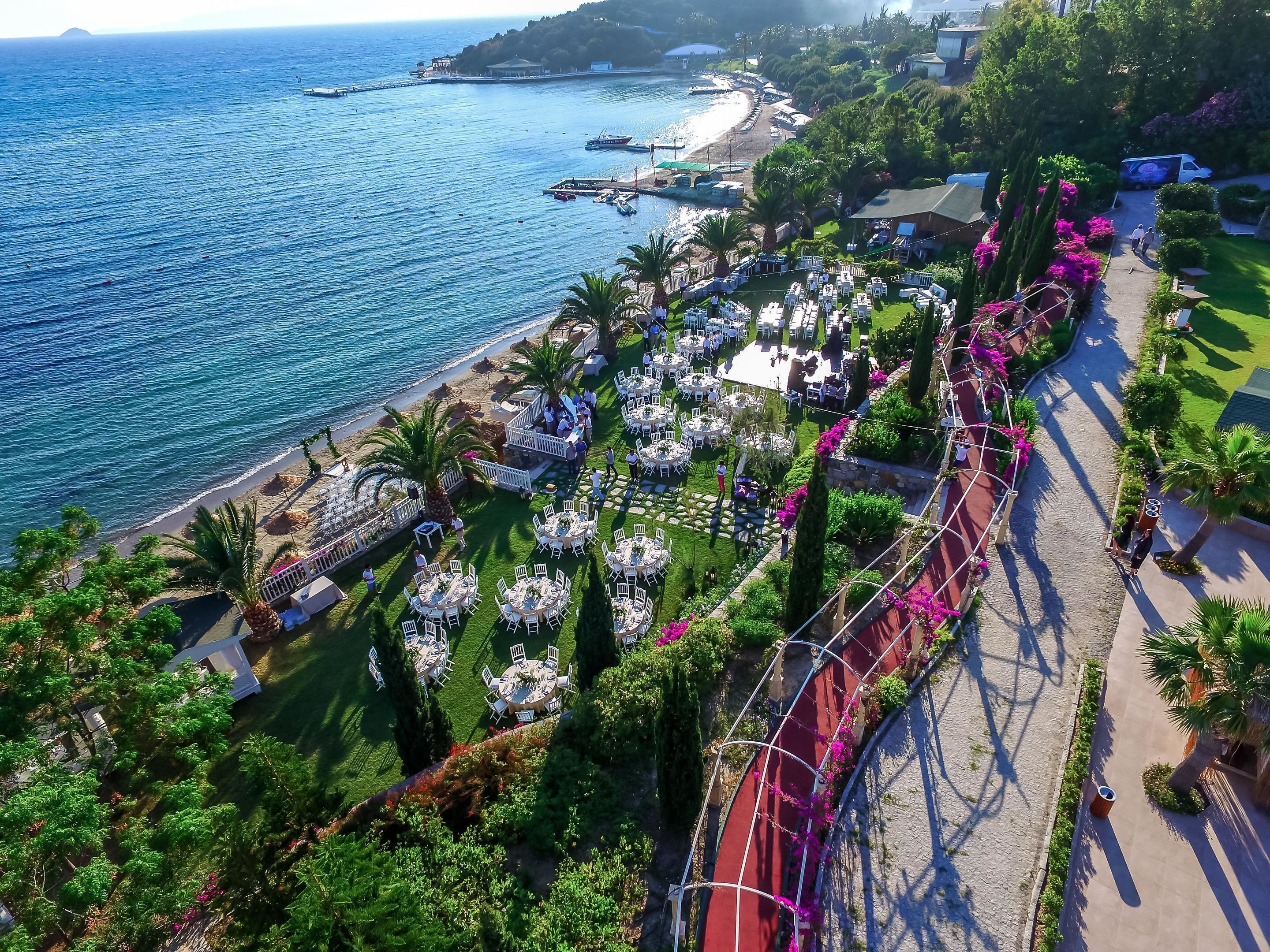 A coastal resort with outdoor dining areas, a beach, and a view of the sea.